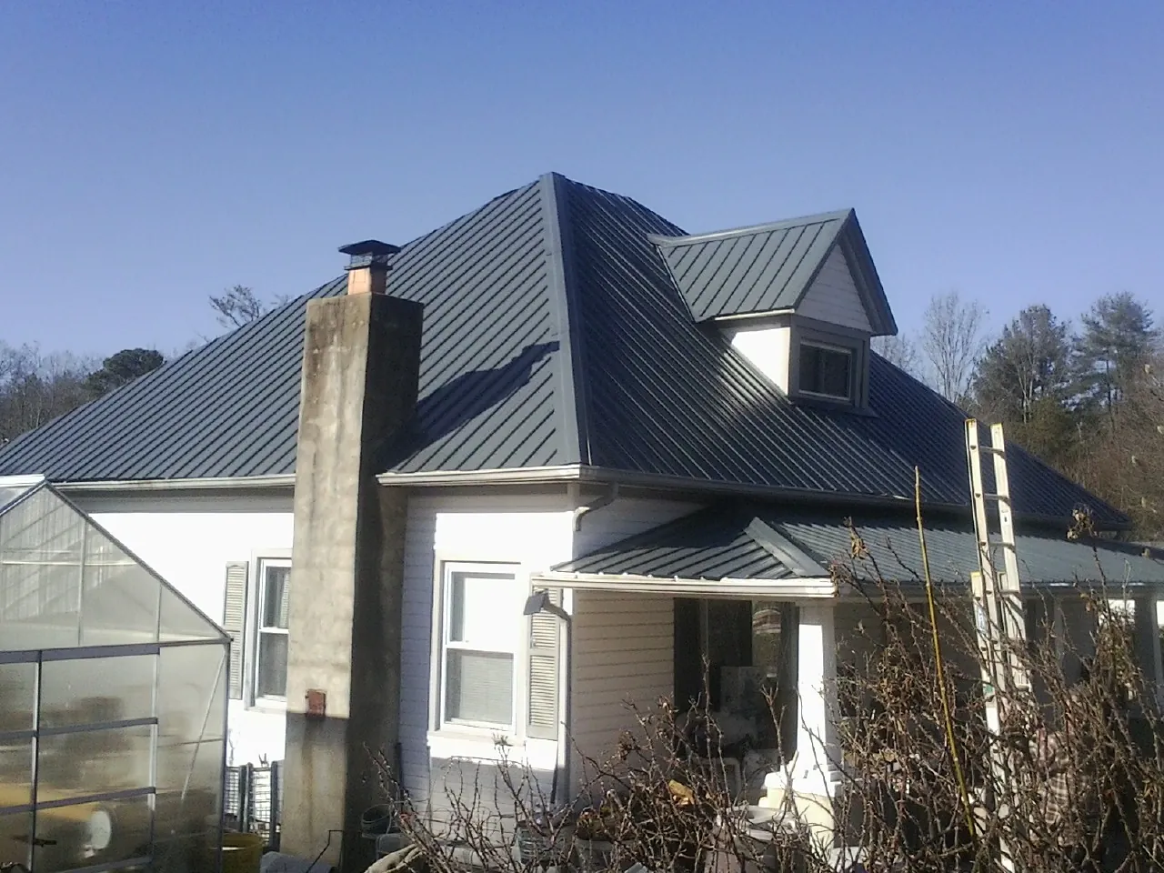 Dark blue standing seam metal roof on a white farmhouse with dormer — Slate & Tile Roof Repair by Roofing Brothers in Capistrano Beach